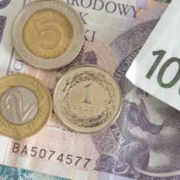 Banknot 100 euro oraz monety 1, 2 i 5 złotych na tle banknotów polskich złotych, zdjęcie wykonane we Wrocławiu.