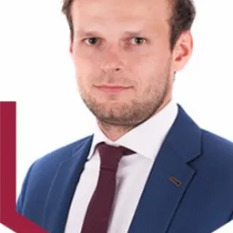 Portret młodego mężczyzny w niebieskiej marynarce i bordowym krawacie, z delikatnym uśmiechem, na białym tle z bordowym akcentem graficznym, Wejherowo.