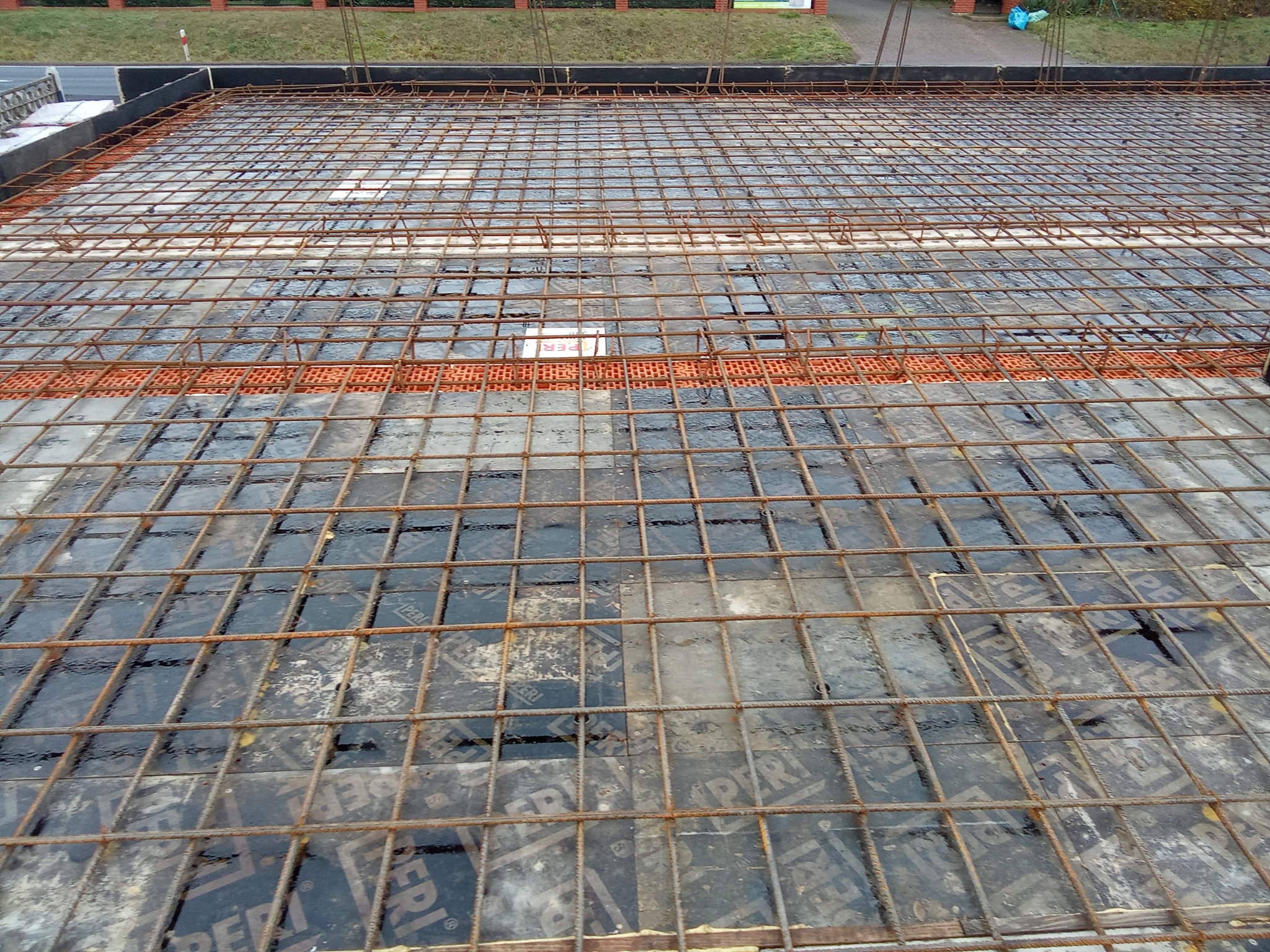 Zbrojenie płyty fundamentowej na budowie w Osiek Wielki. Widoczna siatka z prętów stalowych na deskowaniu. Przygotowanie do wylewania betonu.