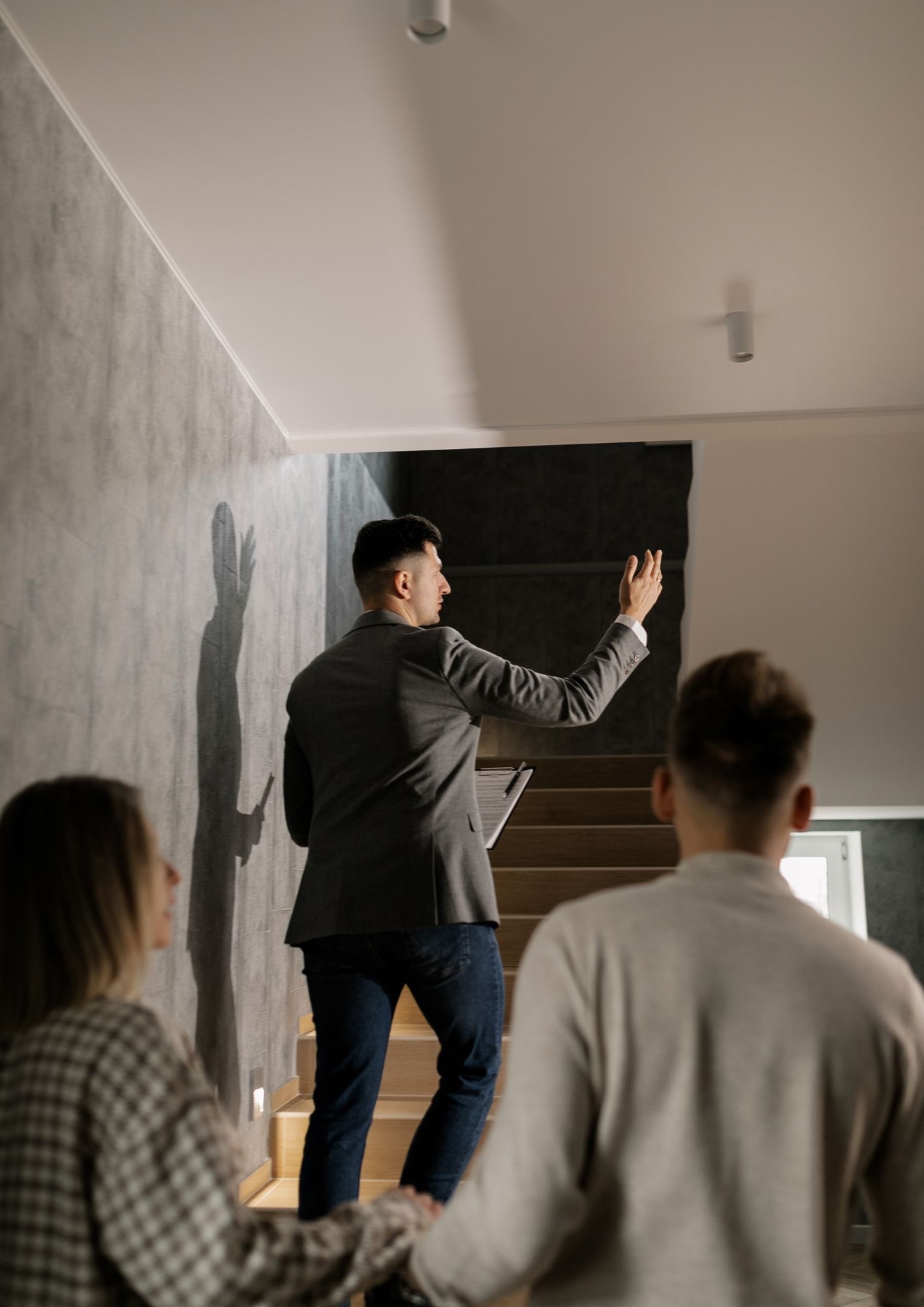 Agent nieruchomości prezentuje wnętrze domu parze, wskazując na detale wykończenia na schodach.