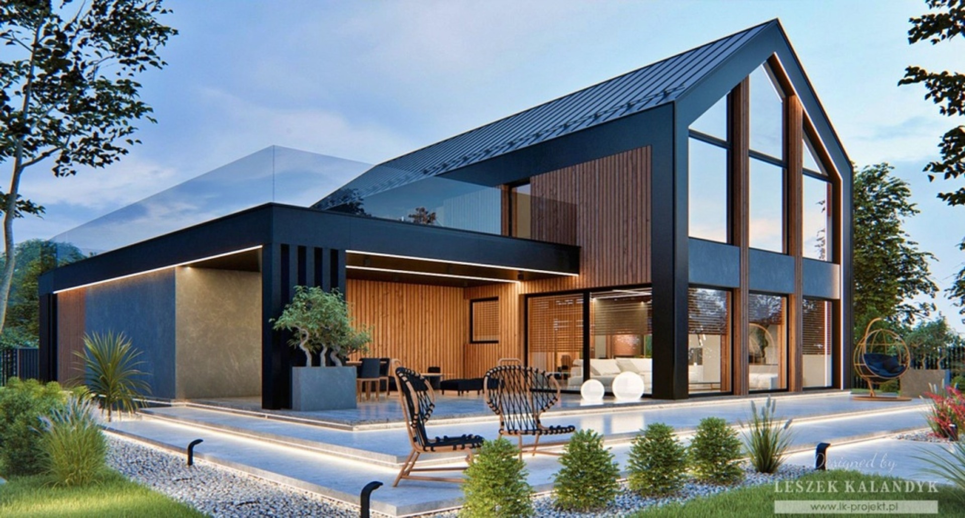 Nowoczesny dom z elementami drewna, duże okna, taras z oświetleniem LED w podłożu, minimalistyczny ogród. Widoczny fragment logo projektanta w prawym dolnym rogu.