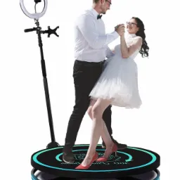 Para młoda tańczy na obrotowej platformie 360 stopni z oświetleniem LED i uchwytem na telefon z lampą pierścieniową.