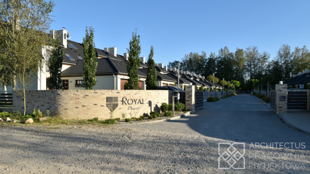 Osiedle domów jednorodzinnych w zabudowie szeregowej, widok z drogi wjazdowej z murem i logo 'Royal Degile'.