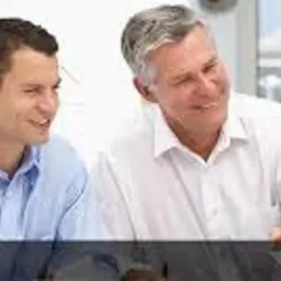 Grupa uśmiechniętych profesjonalistów w jasnych koszulach, w trakcie spotkania w biurze z widokiem na okno.