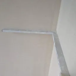 Świeżo wykończony narożnik ściany i sufitu z zamontowanym profilem narożnikowym, gotowy do dalszej obróbki.