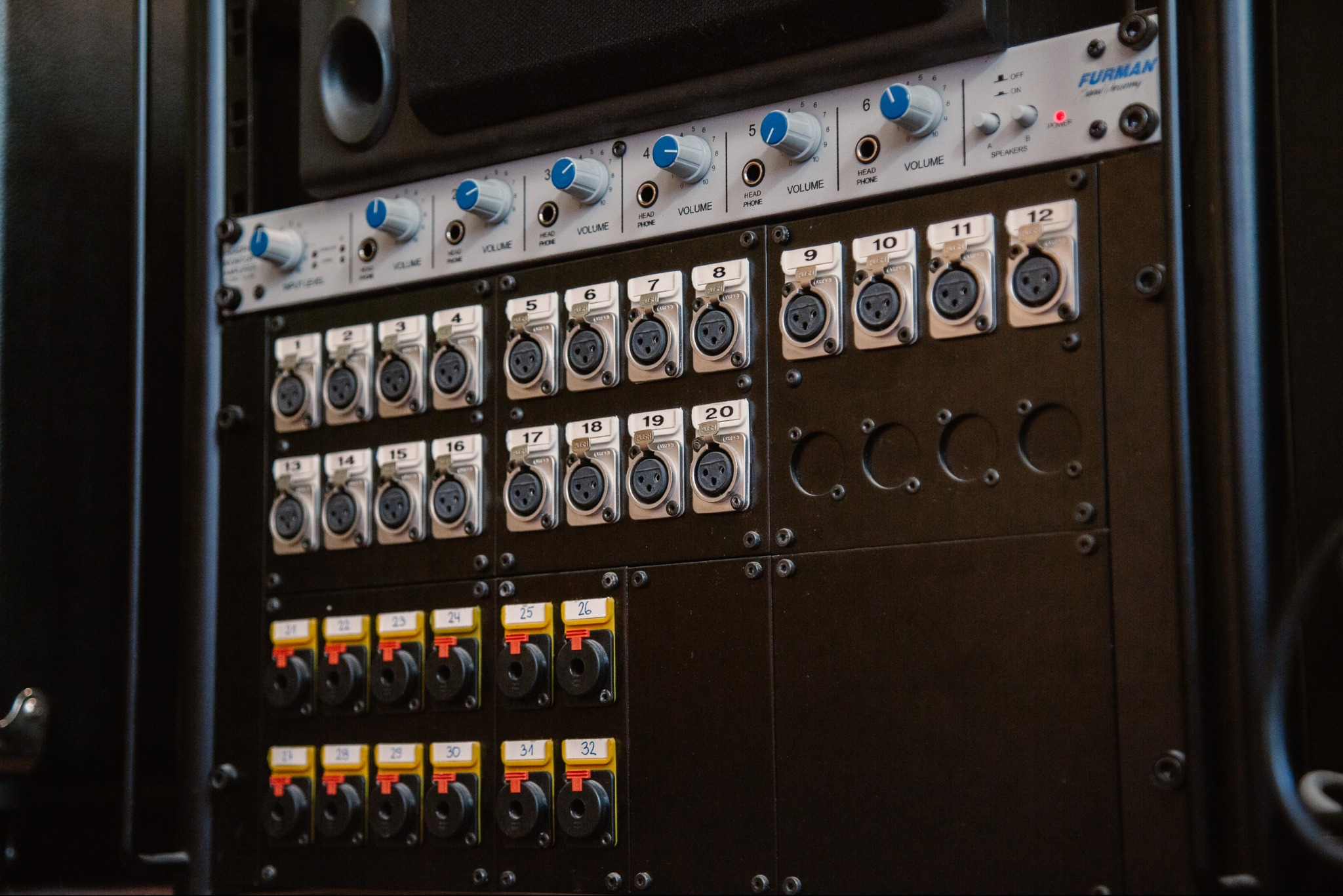 Panel krosowniczy Furman z gniazdami XLR i TRS, regulatory głośności słuchawek, używany w studio nagrań. Widoczne numery portów i oznaczenia funkcji.