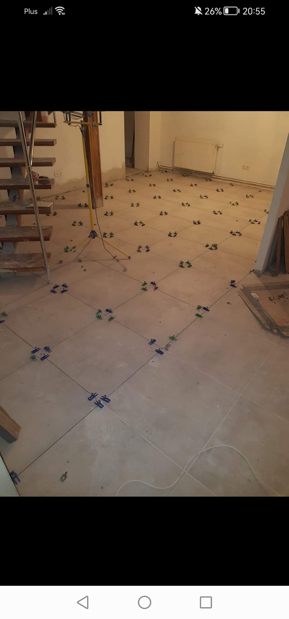 Przygotowanie podłoża pod parkiet: wyrównana wylewka z widocznymi liniami podziału i klipsami dystansowymi, schody w tle.