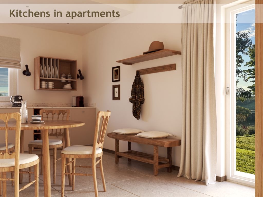 Jasna kuchnia z drewnianymi meblami: okrągły stół z krzesłami, półka na naczynia, wieszak z kapeluszem i kurtką. Za oknem widok na zieleń.