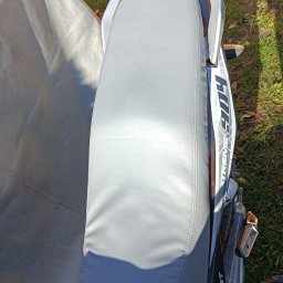 Usługi kaletnicze i szewskie - Szare, skórzane siedzisko motocykla z widocznym szwem, umieszczone na tle trawy i plandeki, ze szczegółami ramy motocykla i napisem 'XTREME 904'