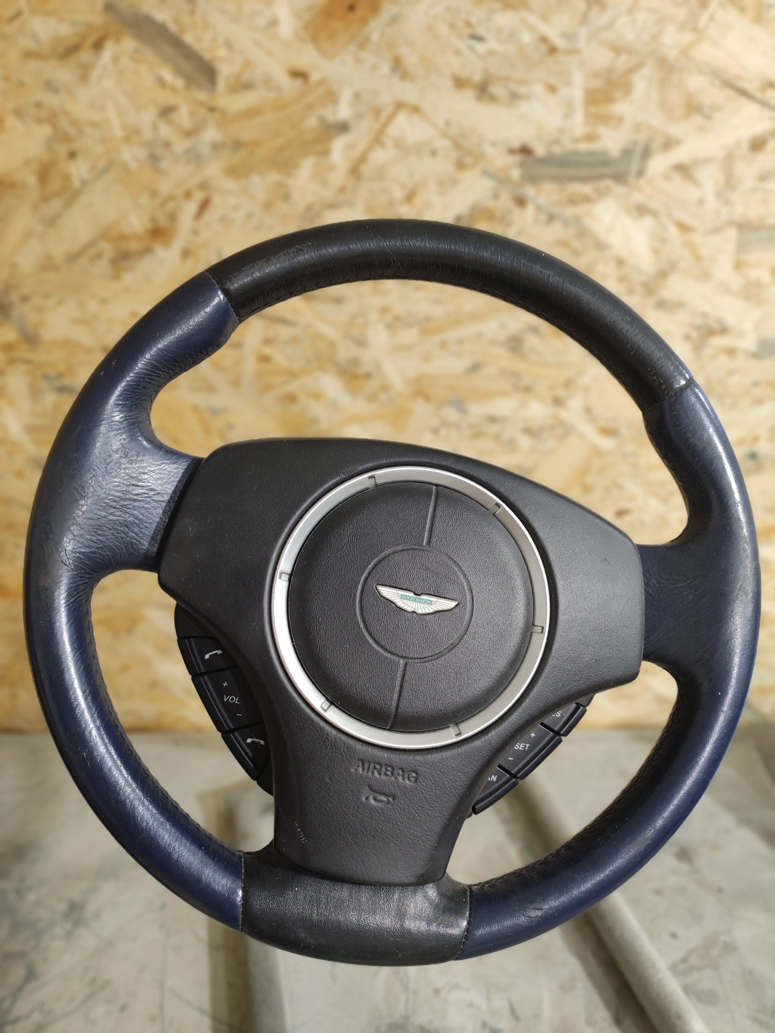 Odnowiona, dwukolorowa kierownica samochodowa z logo marki, z widocznymi przyciskami sterowania i napisem AIRBAG.