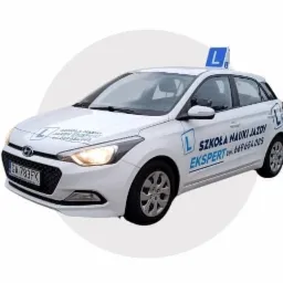 Biały samochód z niebieskim znakiem 'L' na dachu i napisem 'Szkoła Nauki Jazdy Ekspert' z numerem telefonu na boku, tablica rejestracyjna GA 783FK, na białym tle.