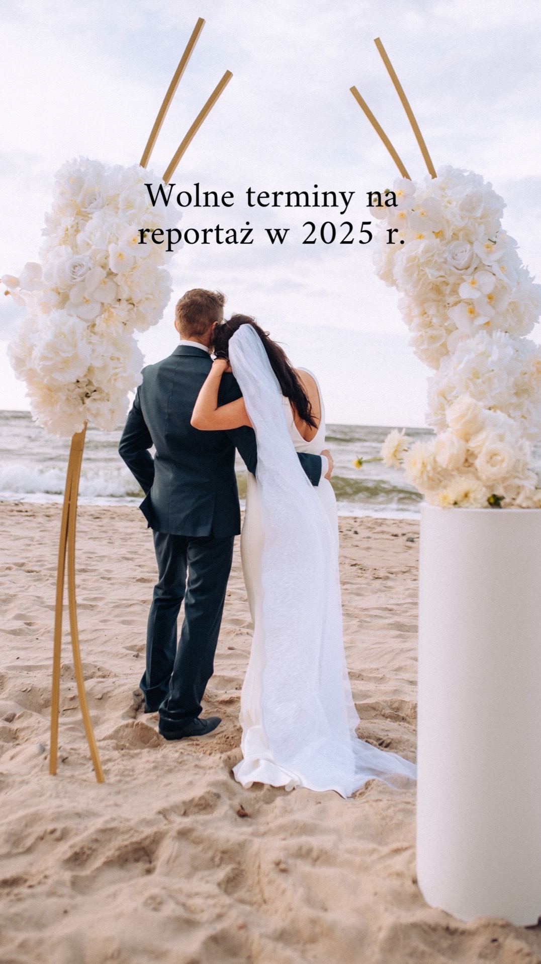 Para młoda w objęciach na plaży pod kwiatowym łukiem z napisem 'Wolne terminy na reportaż w 2025 r.'