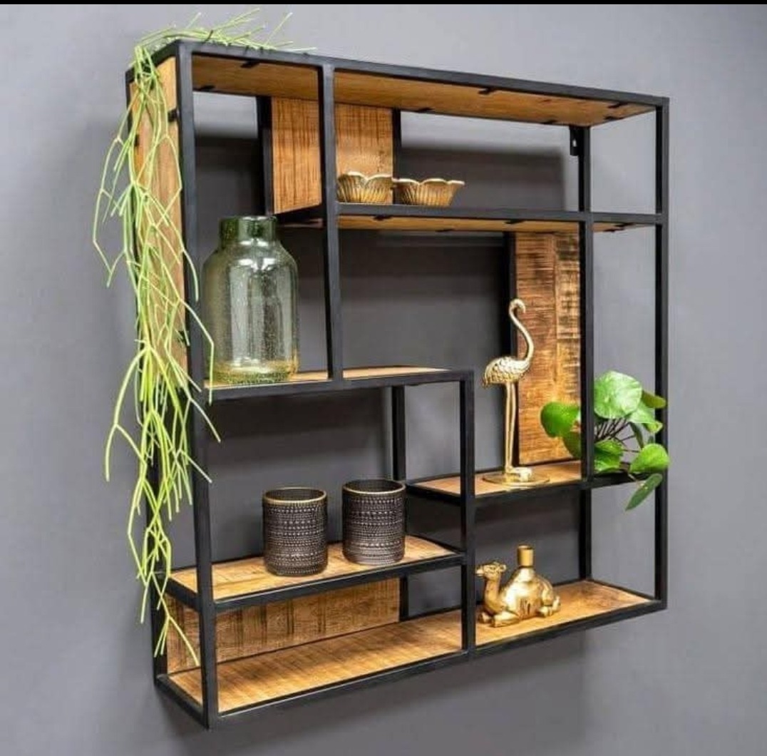 Półka ścienna z metalową ramą i drewnianymi półkami, na której znajdują się dekoracyjne przedmioty: szklany wazon, złote figurki flaminga i wielbłąda, doniczka z rośliną oraz dwie zdobione świece.