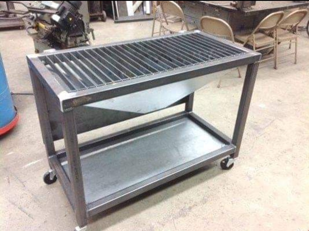 Metalowa konstrukcja na kółkach z rusztem na górze i półką na dole, spawana z profili stalowych, w tle warsztat.