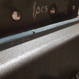 Anatsteel Sp. z o. o. - Spoina łącząca dwie metalowe płyty, na jednej z nich napis '1pcs' oraz otwory, widoczne ślady obróbki.