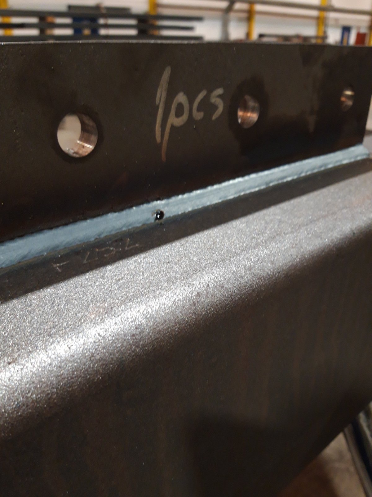 Spoina łącząca dwie metalowe płyty, na jednej z nich napis '1pcs' oraz otwory, widoczne ślady obróbki.