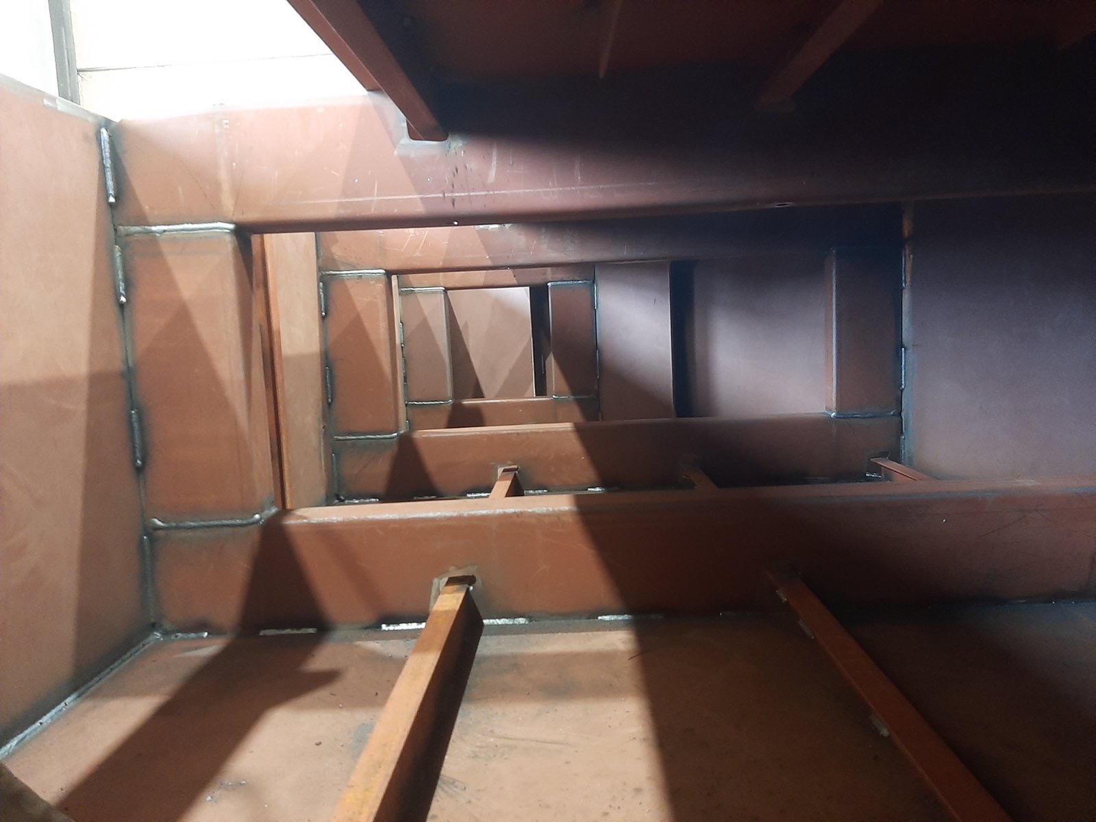 Wnętrze konstrukcji stalowej z widocznymi spawami, wykonane z profili o przekroju prostokątnym, pomalowane farbą w kolorze rdzawym, widok z góry.