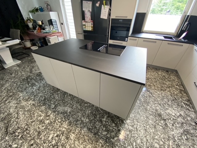 Nowoczesna kuchnia z wyspą i czarnym blatem, widok z góry uwzględniający wzorzystą podłogę.