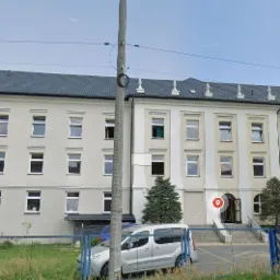 Elewacja budynku biurowego z antenami na dachu, widok z ulicy z zaparkowanymi samochodami.