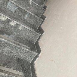 Bauunternehmen Robert Rant - Granitowe schody wewnętrzne z wykończeniem przy ścianie, widoczne ślady zaprawy, surowy stan.