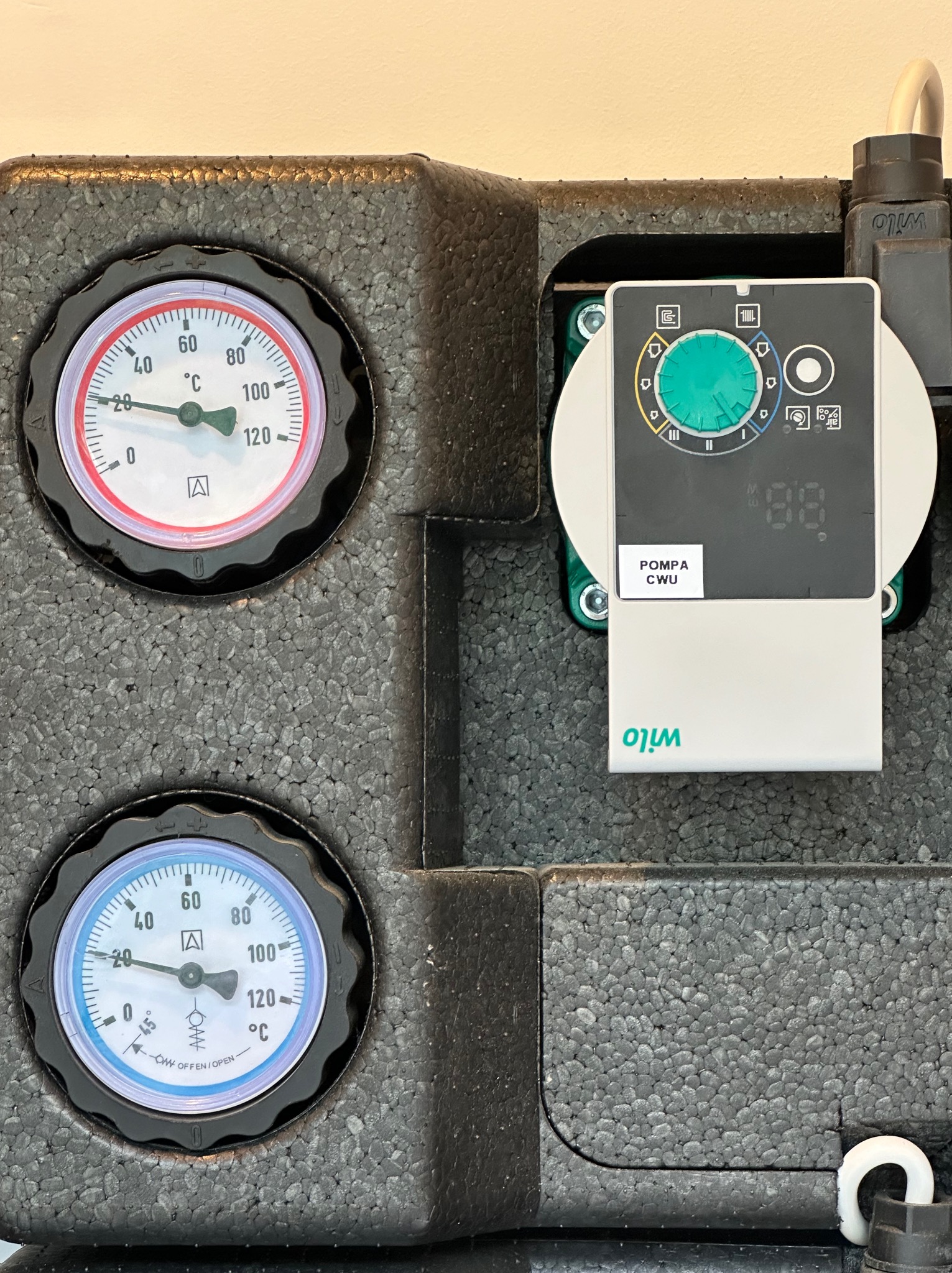 Izolowana pompa obiegowa CWU marki Wilo z dwoma analogowymi termometrami wskazującymi temperaturę, widoczny panel sterowania z wyświetlaczem cyfrowym i pokrętłem regulacji.