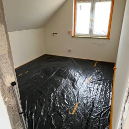 BDR-BUD Sp. Z O.O - Pokój na poddaszu w trakcie remontu: zabezpieczona folią podłoga, okno z folią ochronną, ściany przygotowane do malowania. Widoczne gniazdka elektryczne i surowy fragment ściany.