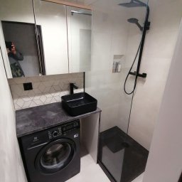 BDR-BUD Sp. Z O.O - Nowoczesna łazienka z czarną armaturą: kabina prysznicowa typu walk-in, umywalka nablatowa na blacie z pralką, lustro z szafką i geometryczne płytki na ścianie.