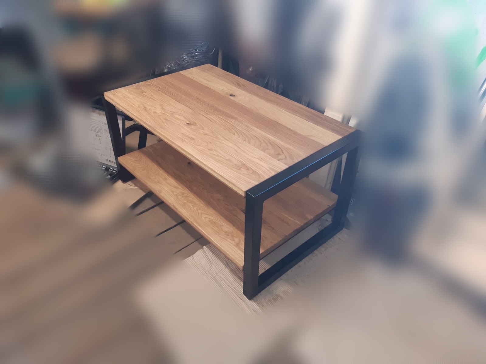 Stolik kawowy z drewna dębowego z czarną metalową ramą, widoczne słoje drewna i półka pod blatem.