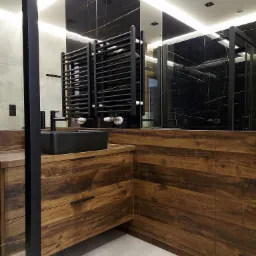 Nowoczesna łazienka z drewnianą szafką pod umywalkę, czarną armaturą i grzejnikiem drabinkowym na tle czarnej ściany z marmurowym wzorem odbijającej się w lustrze.