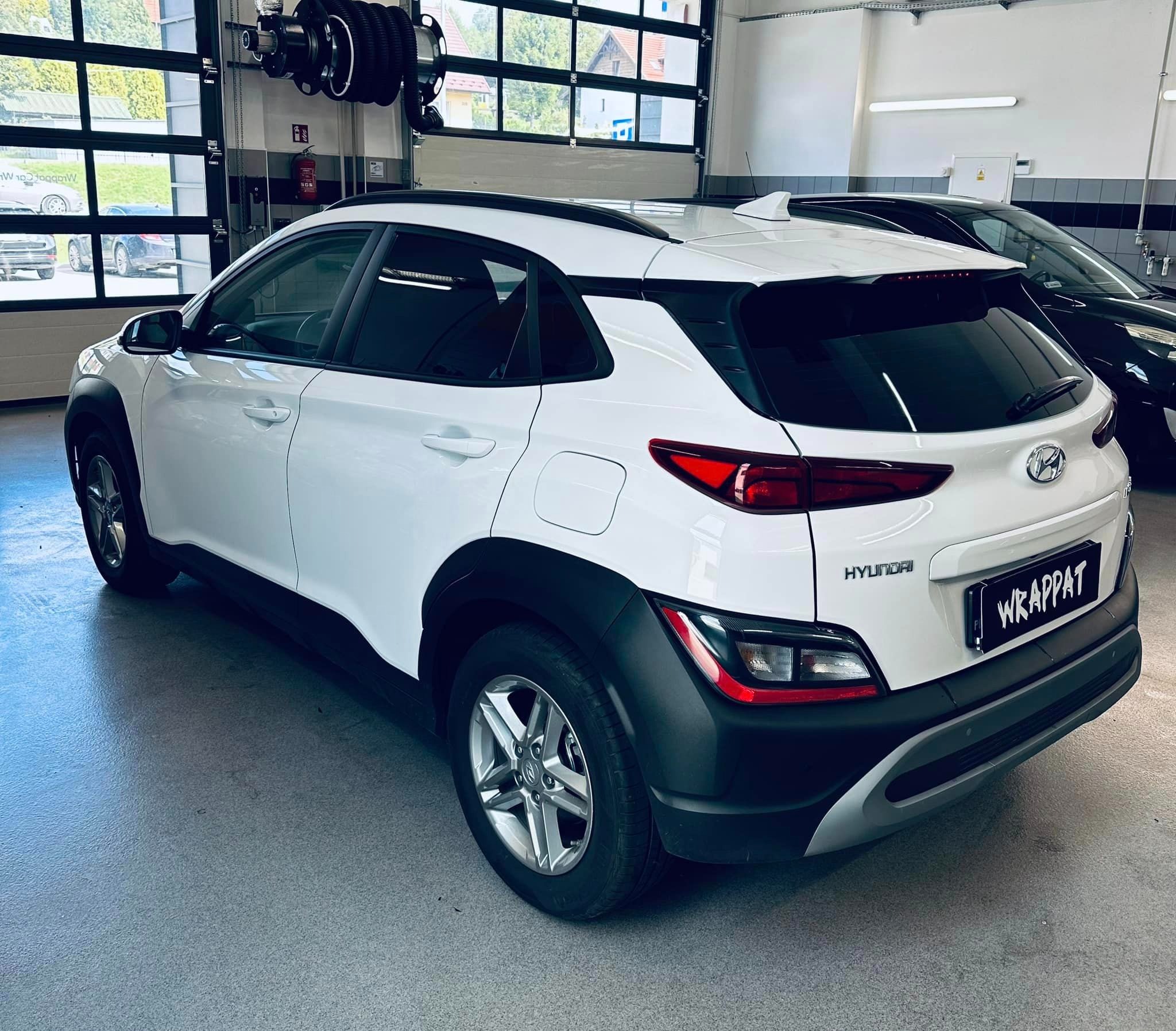 Biały Hyundai Kona w warsztacie, widok z tyłu, z tablicą rejestracyjną 'WRAPPAT'