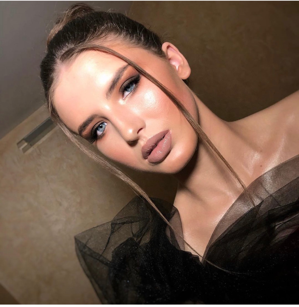 Portret kobiety z profesjonalnym makijażem, uwydatniającym kości policzkowe i podkreślającym niebieskie oczy, włosy upięte w kok, czarna tiulowa kreacja.