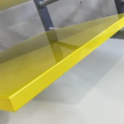 Żółty, lakierowany blat z drewna, zamontowany na metalowym stelażu, widoczny z bliska pod kątem.