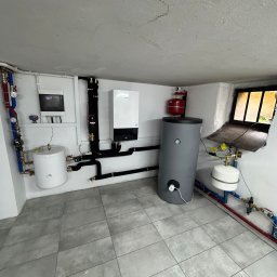 ECO CONNECT SPÓŁKA Z OGRANICZONĄ ODPOWIEDZIALNOŚCIĄ - Zestaw urządzeń grzewczych w kotłowni: zbiornik akumulacyjny, bufor ciepła, pompa obiegowa i rozdzielnica. Instalacja z rur miedzianych i czarnych. Wykończona posadzka.