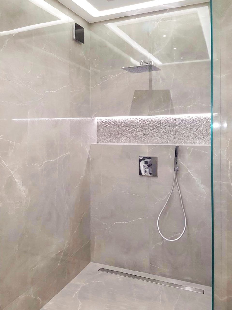 Nowoczesna kabina prysznicowa z szarymi marmurkowymi płytkami, deszczownicą i odpływem liniowym w Warszawie.