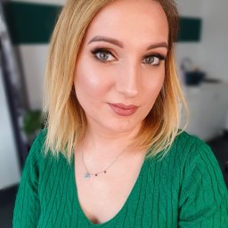 Beauty Center - Portret kobiety z blond włosami w zielonym swetrze, z delikatnym makijażem oczu i błyszczącymi ustami, patrzącej w obiektyw.