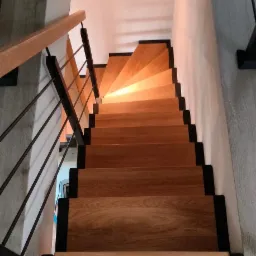 Drewniane schody z metalową balustradą, widok z g&oacute;ry, stopnie oświetlone ciepłym światłem, nowoczesny design.