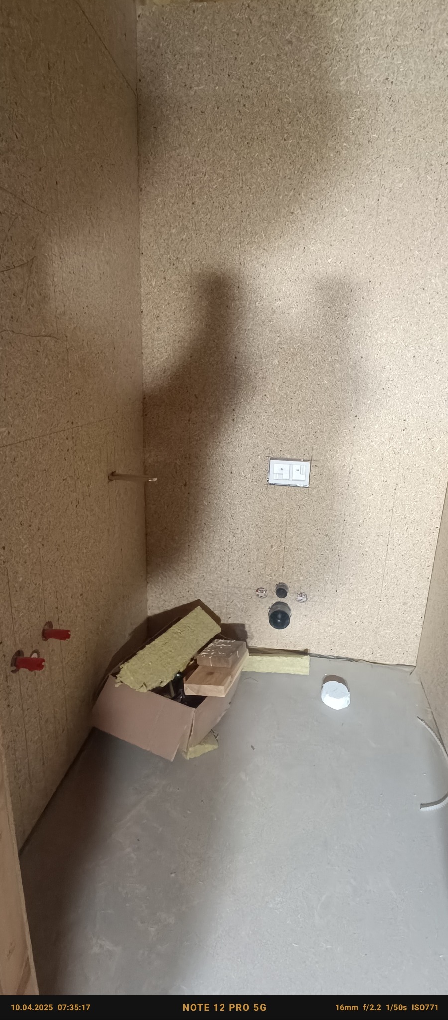 Wnętrze pomieszczenia w trakcie zabudowy płytą MFP, widoczne instalacje, karton z materiałami izolacyjnymi i fragmenty płyt.