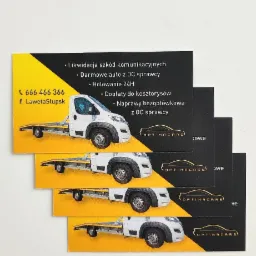 Stos wizytówek firmy z ilustracją lawety, numerem telefonu i informacjami o likwidacji szkód komunikacyjnych oraz holowaniu 24H.