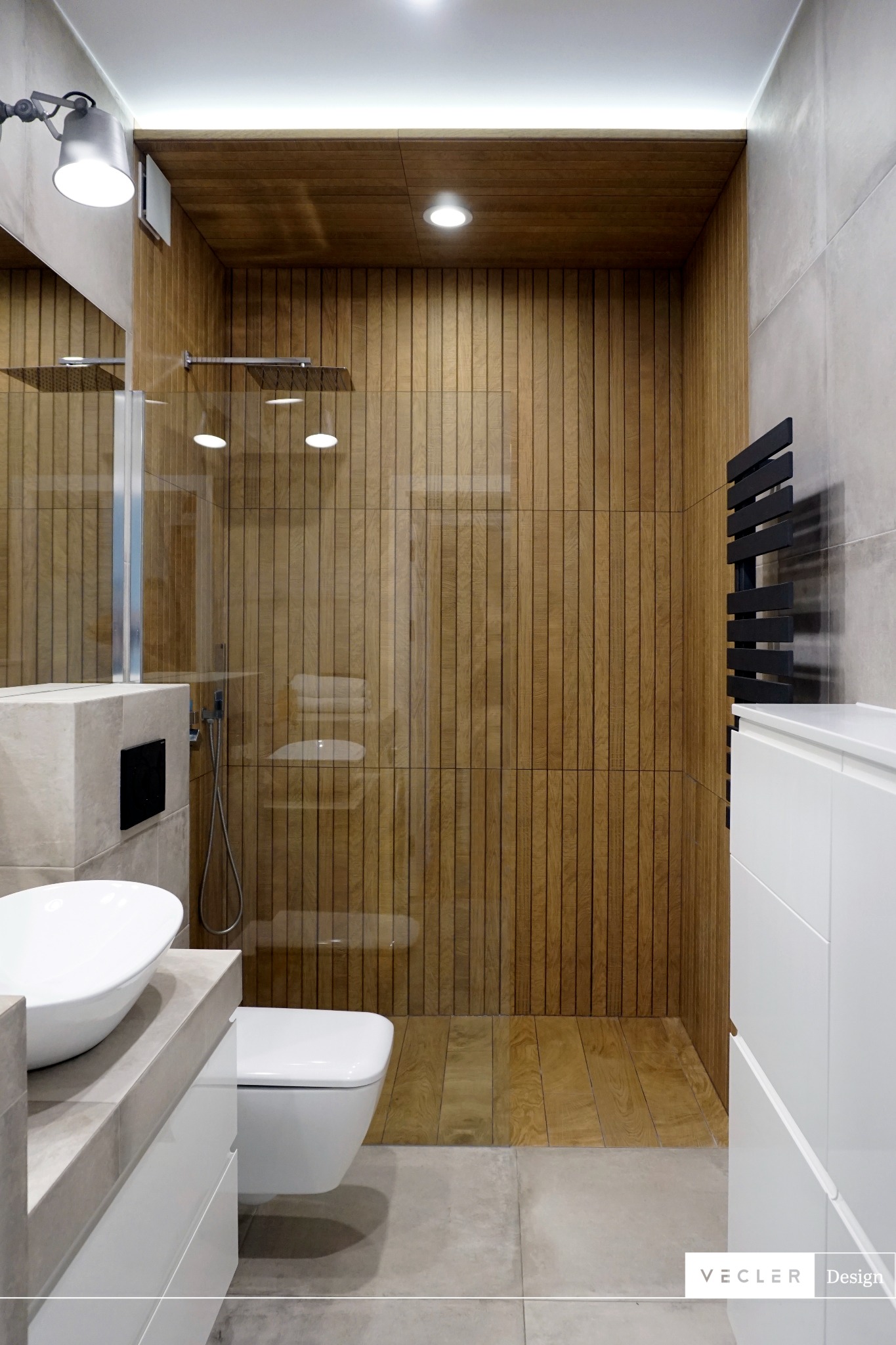 Nowoczesna łazienka z drewnianą okładziną ścienną i podłogową w kabinie prysznicowej, owalna umywalka nablatowa i grzejnik drabinkowy w kolorze czarnym.