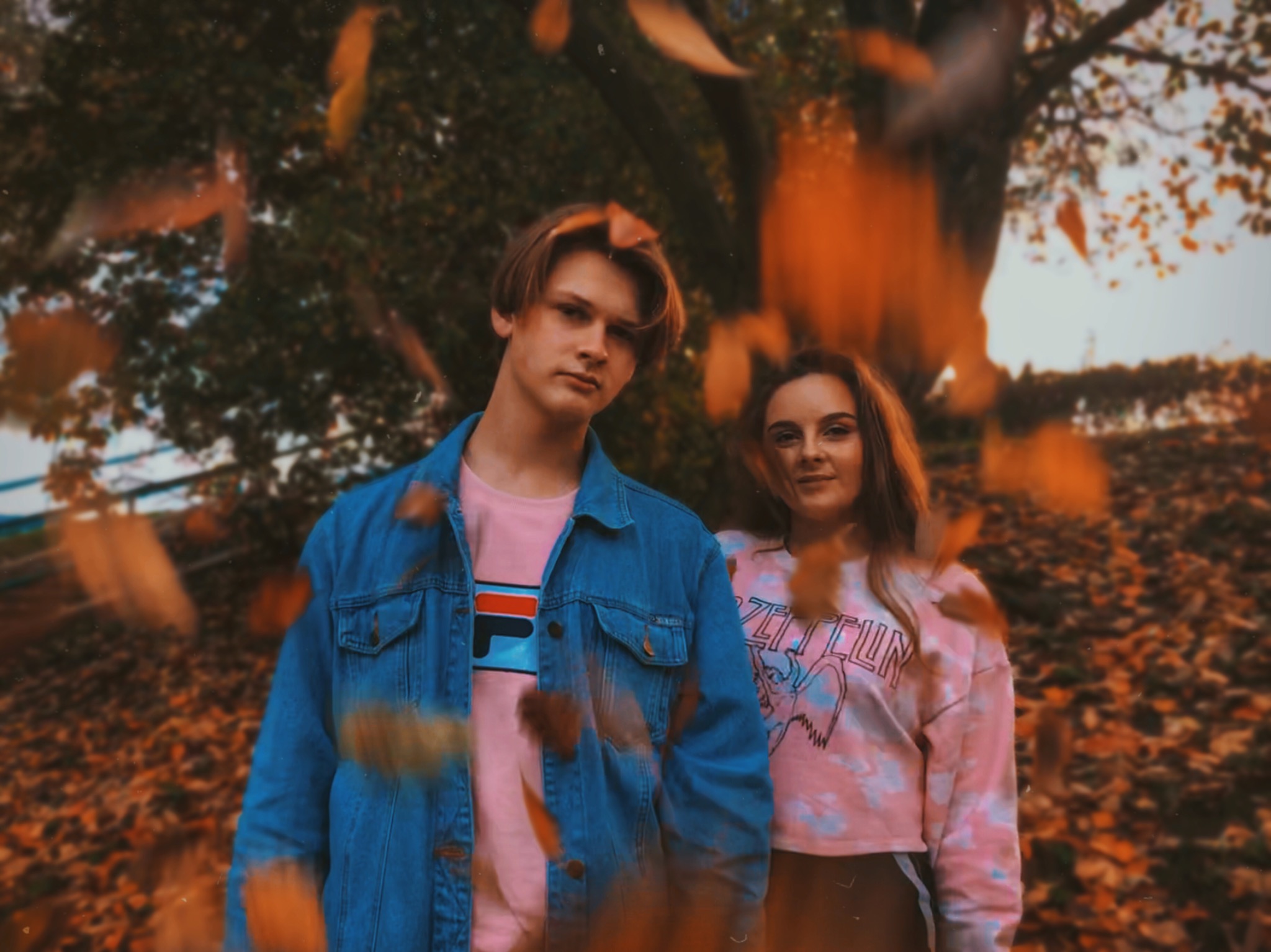 Młoda para w jesiennej scenerii, opadające liście tworzą dynamiczne tło, on w dżinsowej kurtce, ona w bluzie z nadrukiem Led Zeppelin.