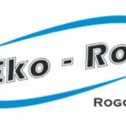 Sztaple ocynkowanych, metalowych paneli ogrodzeniowych na placu składowym, logo firmy Eko-Rol Rogowo w centralnej części zdjęcia.