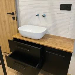 Szafka lakierowana na czarny mat połączona z blatem fornirowanym oraz matowymi uchwytami prezentuje się pięknie