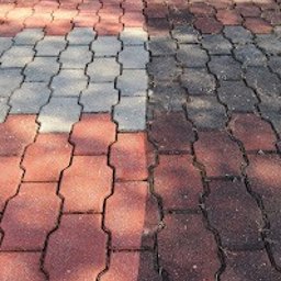 Kajetan Smoliński Nordlys - Częściowo oczyszczona, czerwono-szara kostka brukowa, widoczna różnica w kolorze i czystości między wyczyszczoną a zabrudzoną powierzchnią.