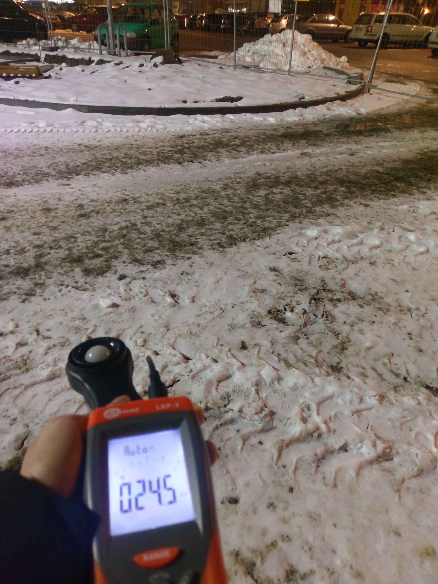 Pomiar natężenia oświetlenia luksomierzem LXP-2 na zewnątrz, w zimowych warunkach; na wyświetlaczu urządzenia widoczna wartość 0245 lx.