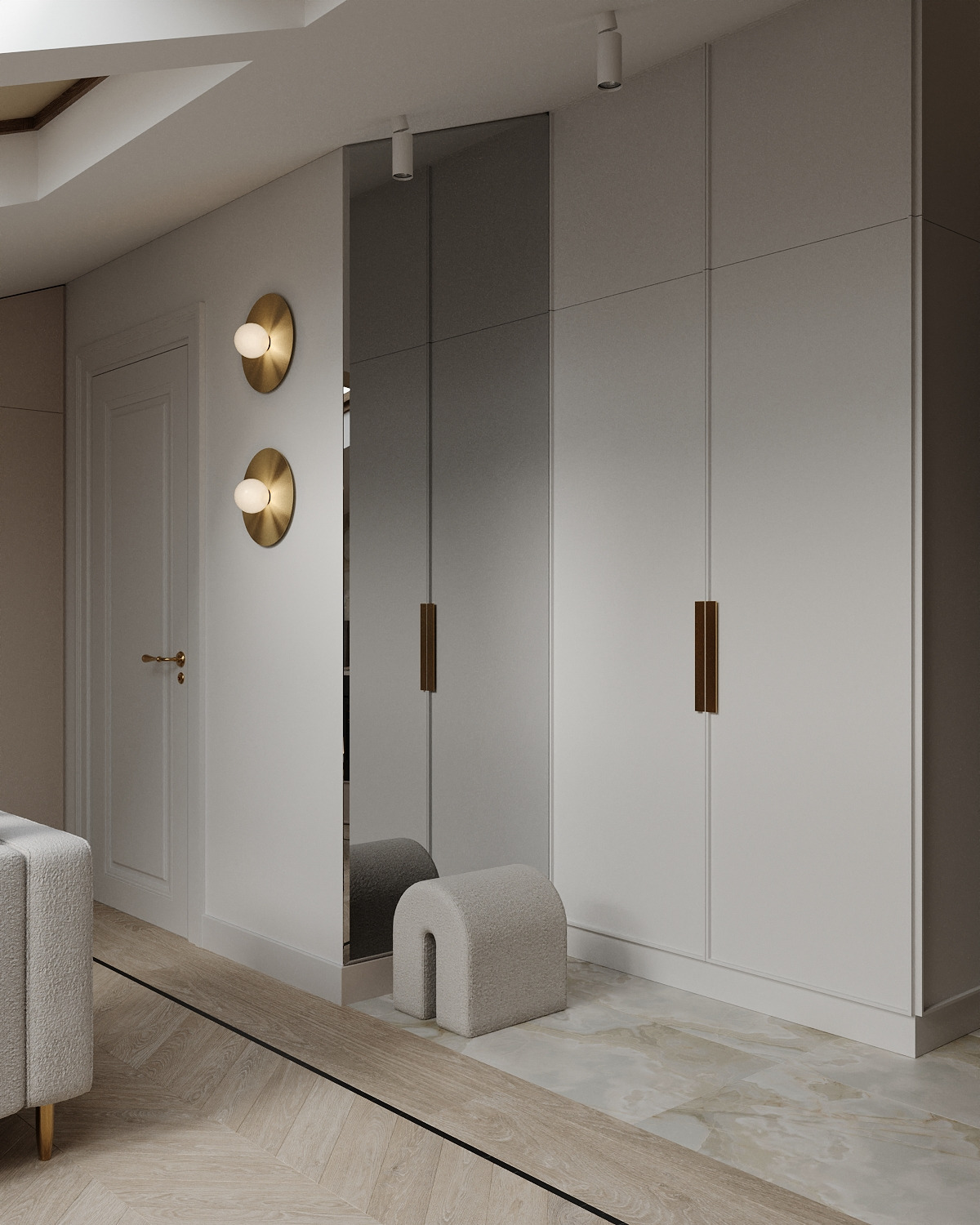 Nowoczesne wnętrze: biała szafa w zabudowie z lustrzanymi drzwiami, okrągłe, złote lampy ścienne, tapicerowany puf w kształcie łuku, parkiet w jodełkę i marmurowa posadzka.