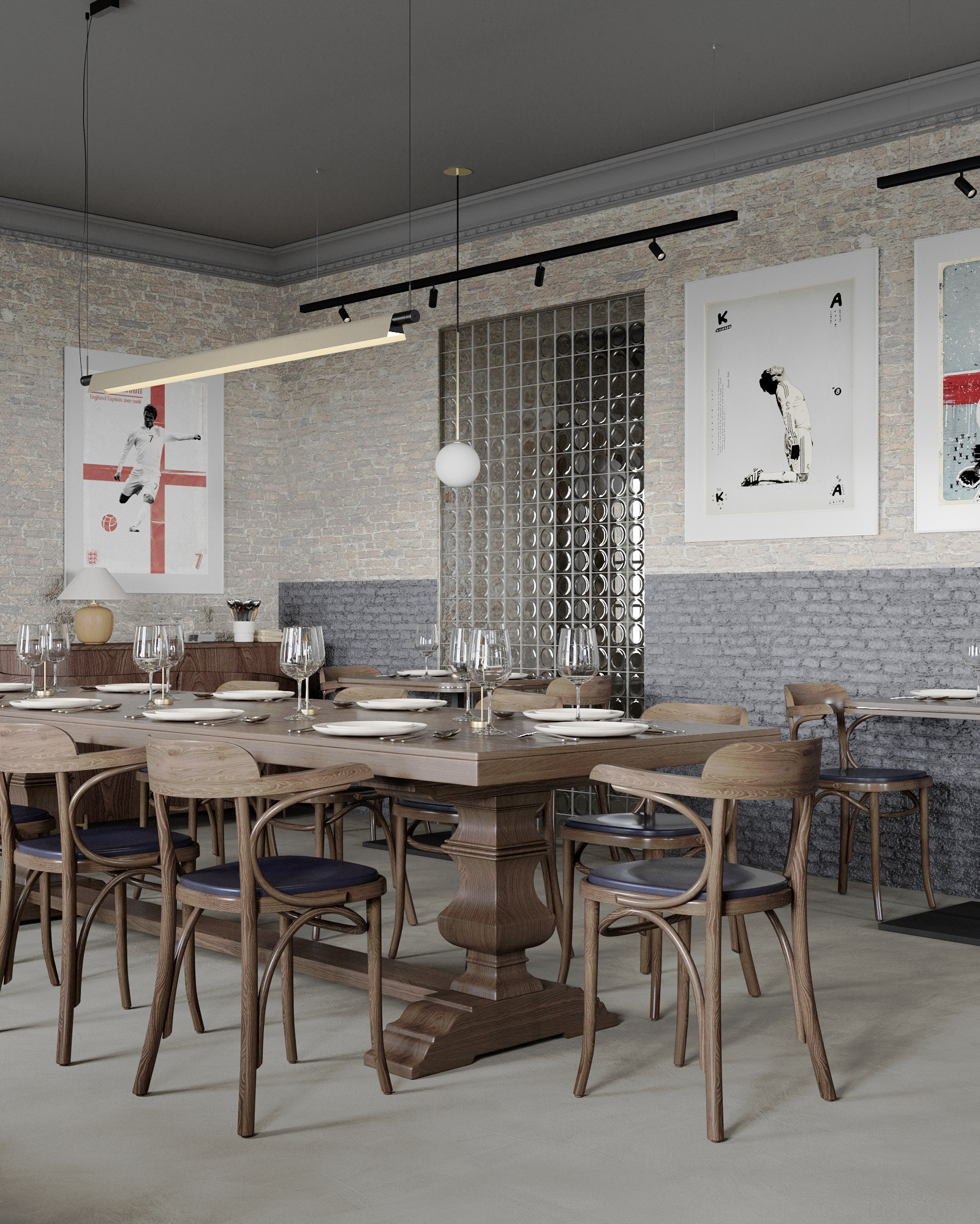 Wnętrze restauracji z dużym drewnianym stołem nakrytym dla wielu osób, krzesła z giętego drewna z granatowymi siedziskami, ceglana ściana z abstrakcyjnymi plakatami i szklana ścianka działowa.