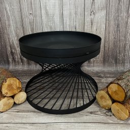 Metal&Wood Art Maciej Gierszewski - Czarny, metalowy kosz na ognisko z spiralną podstawą, otoczony ułożonymi kawałkami drewna na tle drewnianej ściany.