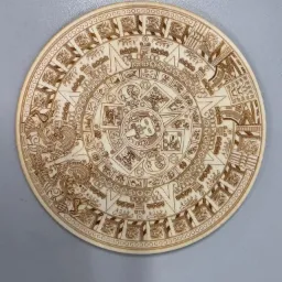 Drewniany kalendarz Majów, wykonany we Wrocławiu, z precyzyjnymi wzorami wypalonymi laserowo, leżący na szarym tle.