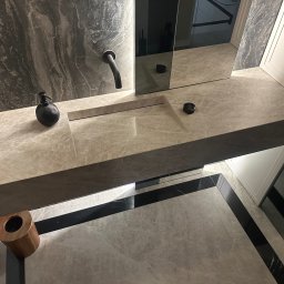 Comfort Lux - Nowoczesna łazienka z marmurową umywalką wpuszczoną w blat, czarną armaturą i dodatkami oraz podłogą wykończoną płytkami z czarnymi akcentami.