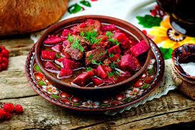 Bordowa zupa z buraków i mięsa w glinianej misce, udekorowana zieloną pietruszką, na drewnianym stole z ludowym obrusem i dekoracjami.